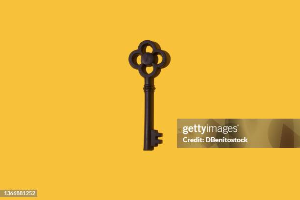 black color vintage key with hard shadow on yellow background. concept of opening, door, buying, mortgage, rent and rent. - ornate key stock pictures, royalty-free photos & images