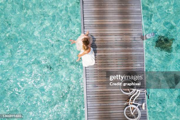 two friends sitting side by side on jetty - couple jetty stock pictures, royalty-free photos & images