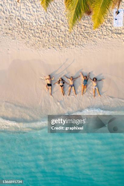 aerial view of friends lying down on the beach - maldives stock pictures, royalty-free photos & images