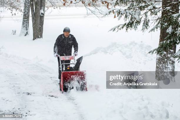 man using snow blower machine to clear driveway. - snow blower stock pictures, royalty-free photos & images