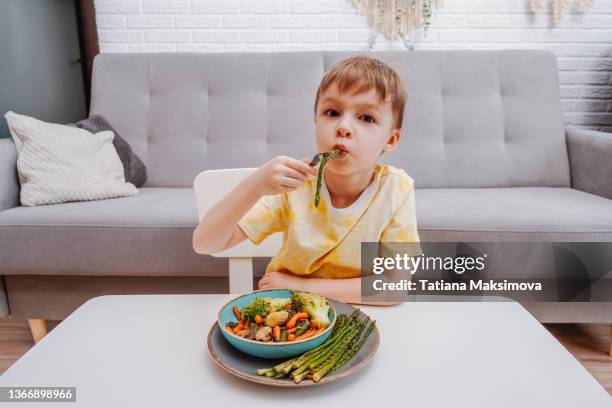 child boy is eating vegetables in living room. - asparagus stock pictures, royalty-free photos & images