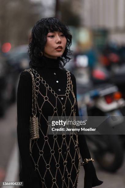 Xiayan wearing a black maxi dress with gold details and black boots outside Paco Rabanne on January 23, 2022 in Paris, France.