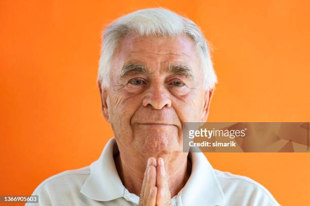 meditating senior man - portrait orange background stock pictures, royalty-free photos & images