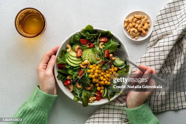 faceless female eating healthy vegan plant-based salad in bowl with fatty acids and dietary fiber - veganist stockfoto's en -beelden