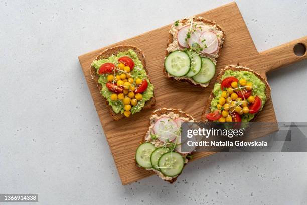 four grain bread toasts with cream cheese and avocado spread on wooden board, copy space - sándwich a la plancha fotografías e imágenes de stock