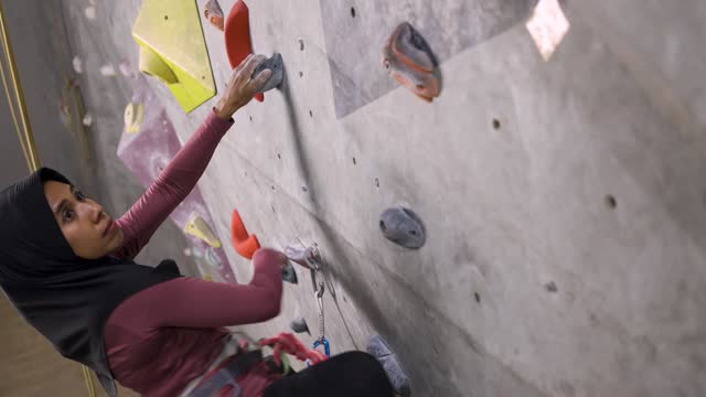 Muslim Rock Climber Climbing Up the Wall at Indoor Gym