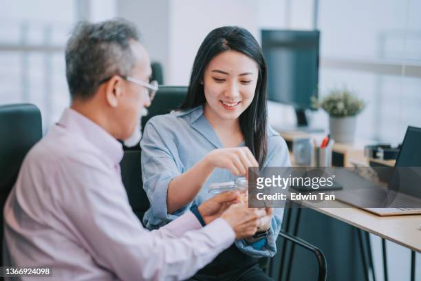 2 asiatische angestellte machen gemeinsam eine pause beim snack am arbeitsplatzbüro - office snack stock-fotos und bilder
