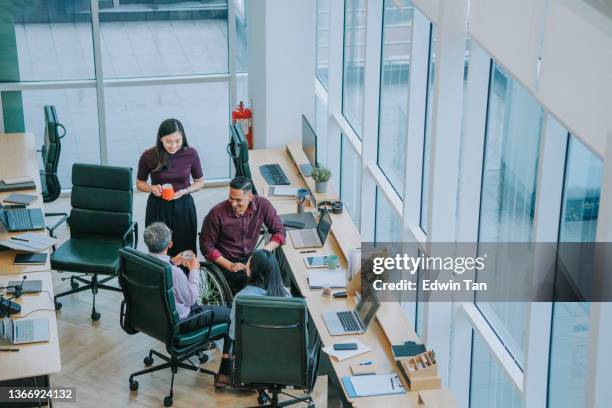 group of asian white collar worker having a break taking snack at the workstation office together - diverse group of asian stockfoto's en -beelden