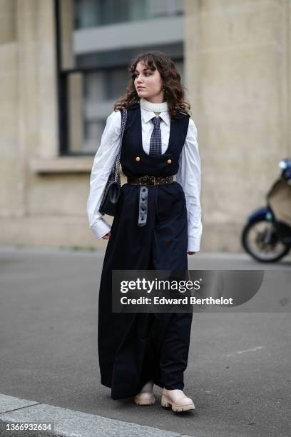 Guest wears a white ribbed wool turtleneck pullover, a white shirt, a black with small gray checkered print pattern tie, a black square-neck /...