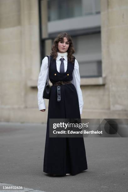 Guest wears a white ribbed wool turtleneck pullover, a white shirt, a black with small gray checkered print pattern tie, a black square-neck /...