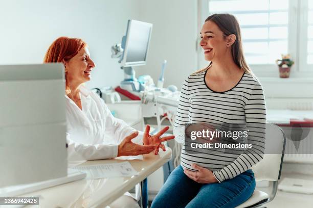 female doctor talking to pregnant woman in office - gynaecologist stock pictures, royalty-free photos & images