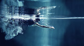 Athlete swimming freestyle on blue background, underwater view
