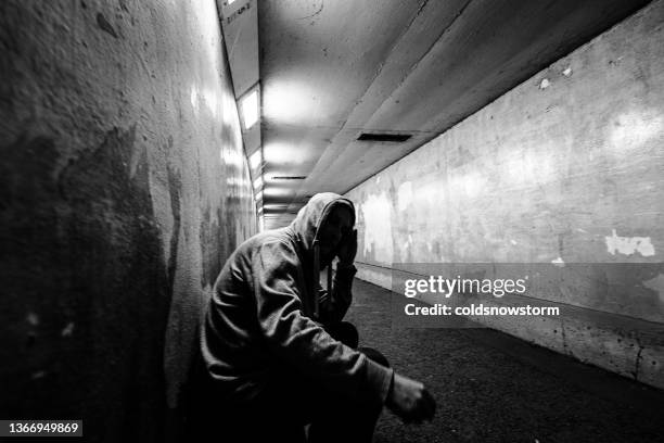 homeless man alone in cold dark subway tunnel in the city - homeless person stockfoto's en -beelden