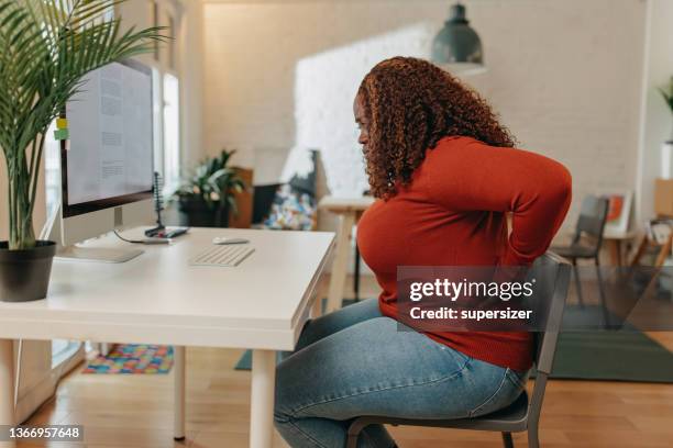 young african-american  woman having back pain - back pain woman stock pictures, royalty-free photos & images