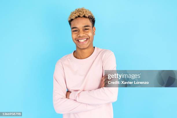 teenage boy looking at the camera and smiling while posing with his arms crossed. - boy portrait studio stock-fotos und bilder