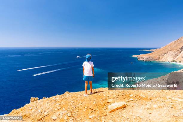 cute little boy admiring the blue sea, crete - boat top view stock-fotos und bilder