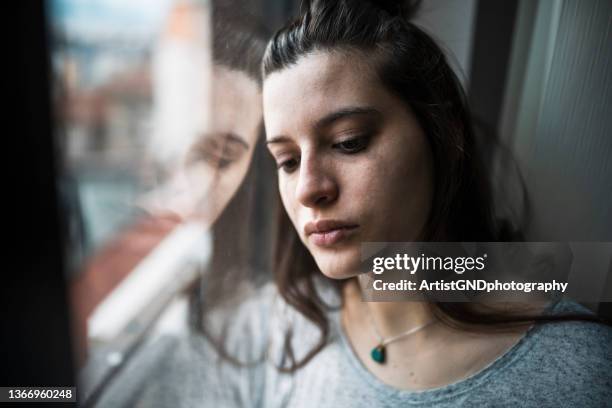 mujer deprimida junto a la ventana. - mirar hacia abajo fotografías e imágenes de stock