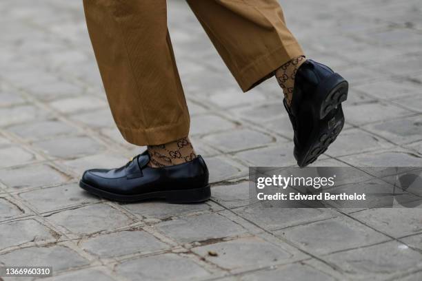 Guest wears brown large denim pants, brown and dark brown GG monogram print pattern socks from Gucci, black shiny leather loafer from Gucci, a ring,...