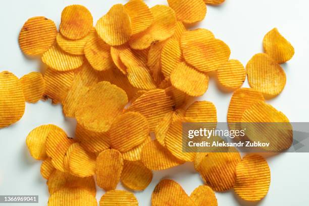 crispy fried potato chips are scattered on a white background or table. corn spicy fatty chips with paprika and spices. the concept of unhealthy diet and lifestyle, accumulation of excess weight. copy space. background of food. - grooved stock pictures, royalty-free photos & images