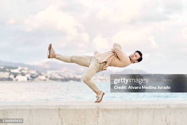 man balancing on leg and folding arms on seafront - dobrado de costas imagens e fotografias de stock