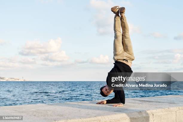 active man doing handstand on seafront - prop sporting position stock pictures, royalty-free photos & images