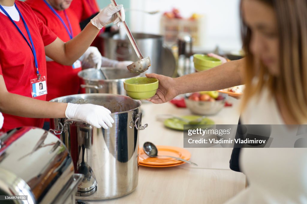A line of hands serving food in a soup kitchen