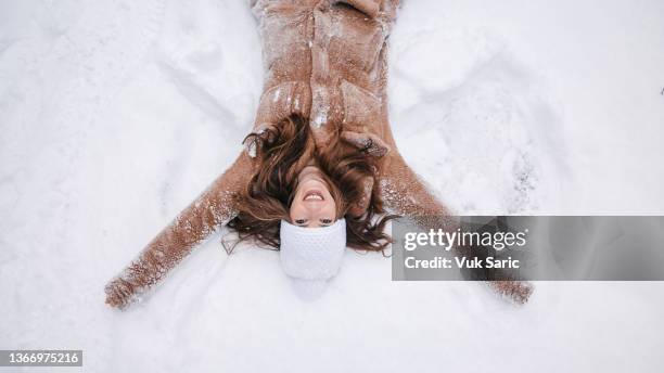 eine junge frau, die einen engel im schnee macht - engel frau stock-fotos und bilder