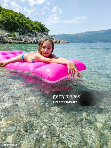 girl on beach holiday on mediterranean sea enjoy  floating on inflatable pink mattress - girls sunbathing 個照片及圖片檔