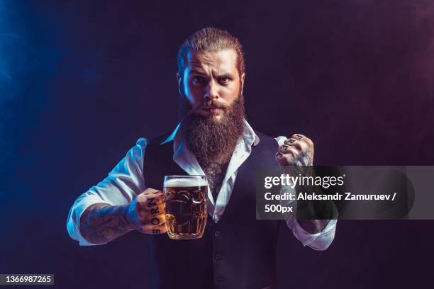 emotional bearded man holds mug of tasty draft beer in hand while - oktoberfest germany stock pictures, royalty-free photos & images