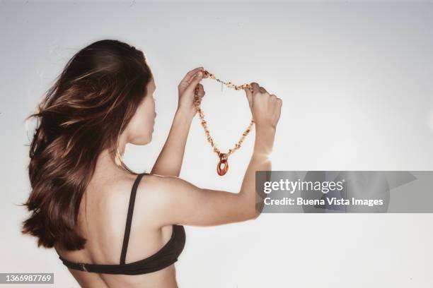 young woman putting on a necklace - collier et femme photos et images de collection