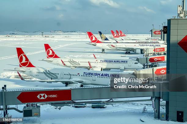 Turkish Airlines planes are seen parked at gates amid heavy snow at Istanbul Airport on January 26, 2022 in Istanbul, Turkey. A large storm brought...