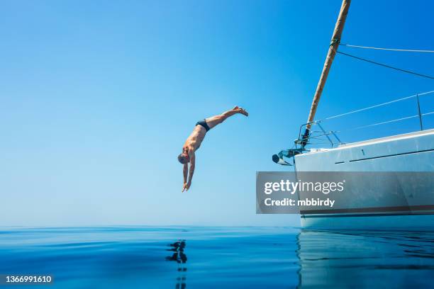 homme de sauter dans la mer depuis un bateau à voile - jumping of boat photos et images de collection