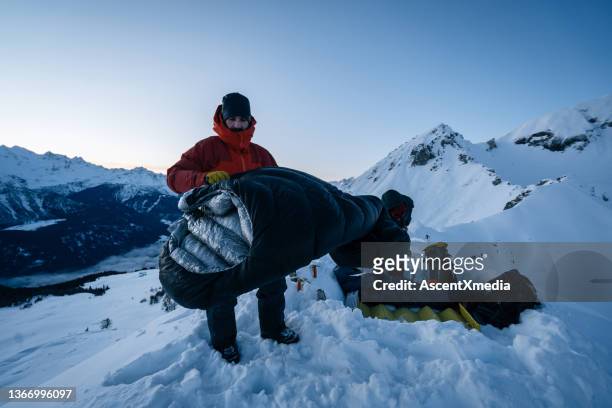 montañero prepara saco de dormir para campamento de invierno en nieve - saco de dormir fotografías e imágenes de stock