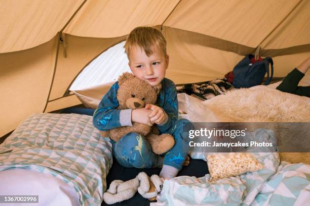 boy hugging teddy bear in tent - bear camping stock pictures, royalty-free photos & images