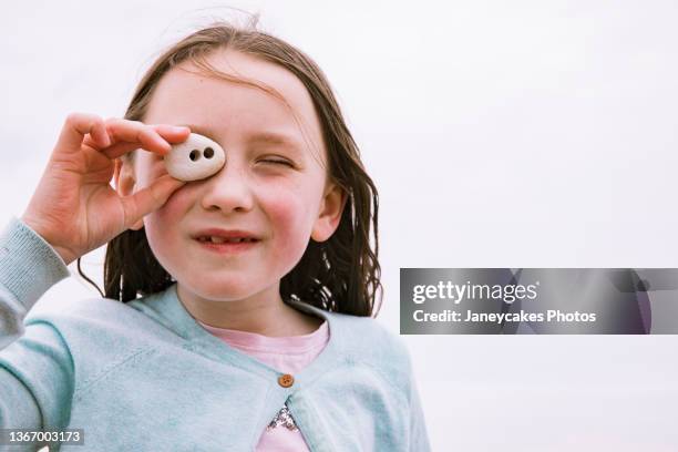 close-up of girl looking through hole in pebble - pebble stock pictures, royalty-free photos & images