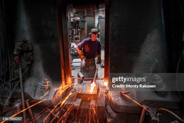 apprentice engineer forging steel parts in hammer press in industrial forge - steelmaking stock pictures, royalty-free photos & images