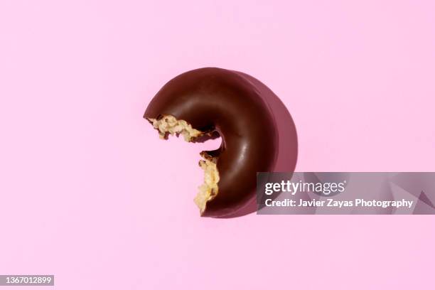 chocolate doughnut on pink colored background - donut stock-fotos und bilder