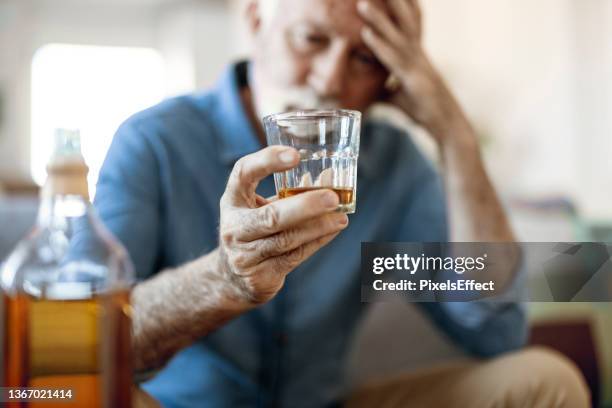 mann trinkt allein zu hause - kater alkohol stock-fotos und bilder