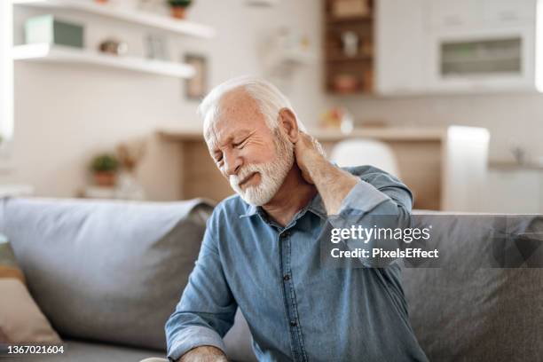 senior man neck and pain - man touching shoulder stockfoto's en -beelden