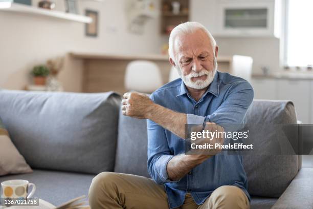 elderly man with elbow pain - gout stockfoto's en -beelden