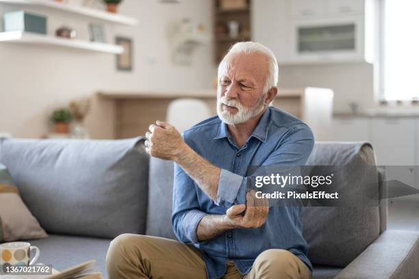 hombre mayor con dolor en el codo - hold wrists fotografías e imágenes de stock