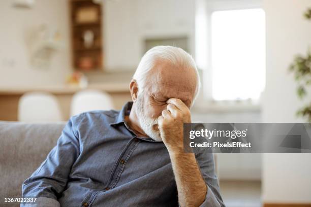 senior man suffering from headache at home - chronic illness stock pictures, royalty-free photos & images