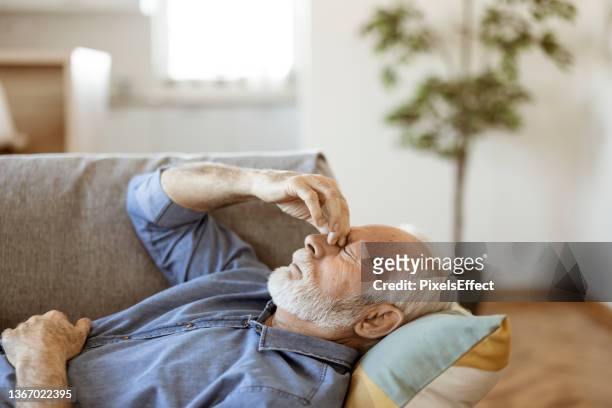 senior man suffering from headache at home - chronic illness stock pictures, royalty-free photos & images