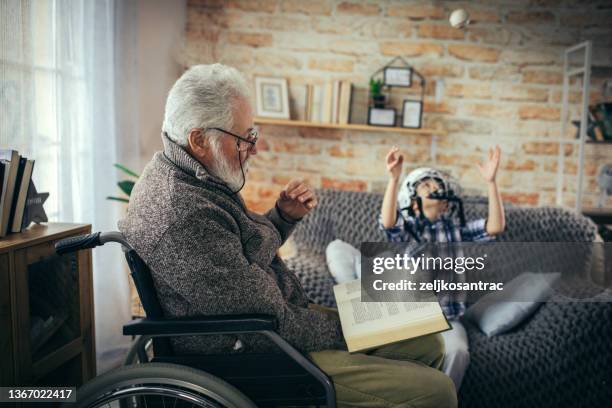 grandfather in wheelchair with his grandson spend time together at home - guitar & medical books stock pictures, royalty-free photos & images