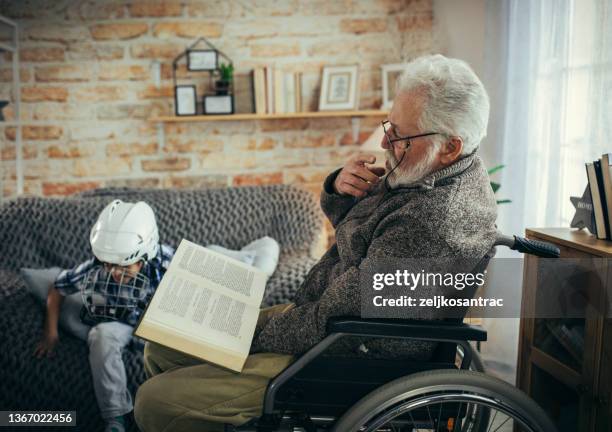 grandfather in wheelchair with his grandson spend time together at home - guitar & medical books stock pictures, royalty-free photos & images