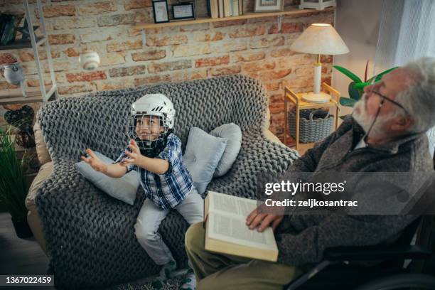 grandfather in wheelchair with his grandson spend time together at home - guitar & medical books stock pictures, royalty-free photos & images