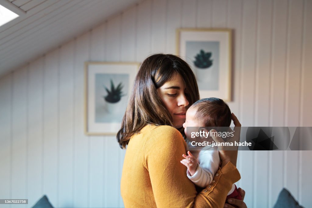 Side view of new mother comforting her newborn while crying.