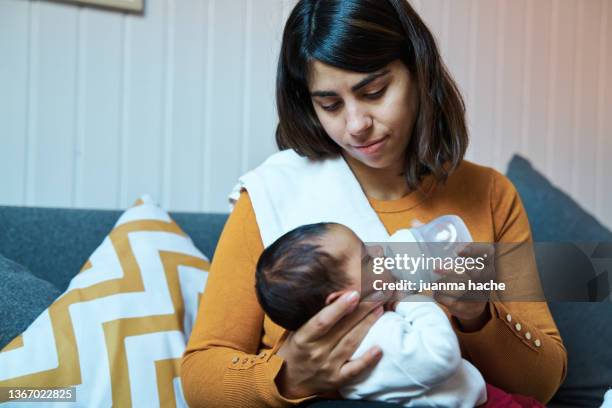 close-up view of mother feeding her baby with infant formula bottle at home. - bottle milk baby stock-fotos und bilder