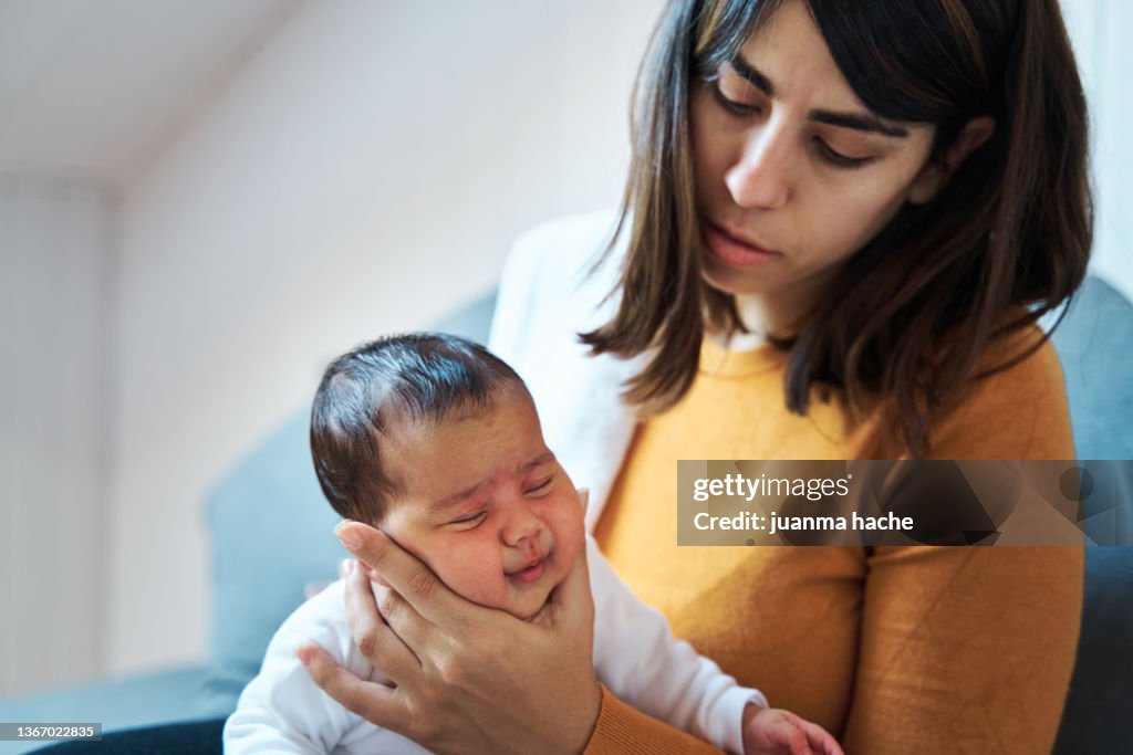 Close-up view of mother holding her baby girl by the face as she burp the baby after eating.
