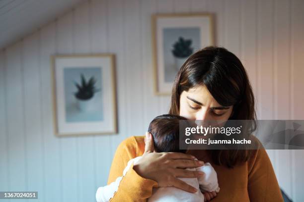 front view of a mother singing a lullaby to her newborn baby for a nap. - chambre nouveau né famille photos et images de collection